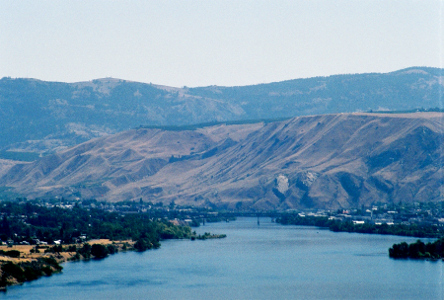 [A view from above the river looking it as it disappears from view as it curves to the left because of the tall cavernous rock on the far shore.]